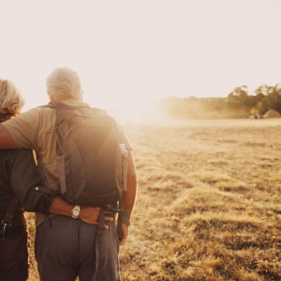 A older couple hiking through a field.
