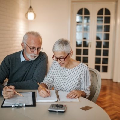 An elderly couple sitting at a table reviewing finances