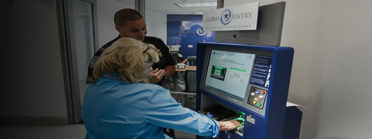 CBP Officer showing a female how to use the global entry kiosk