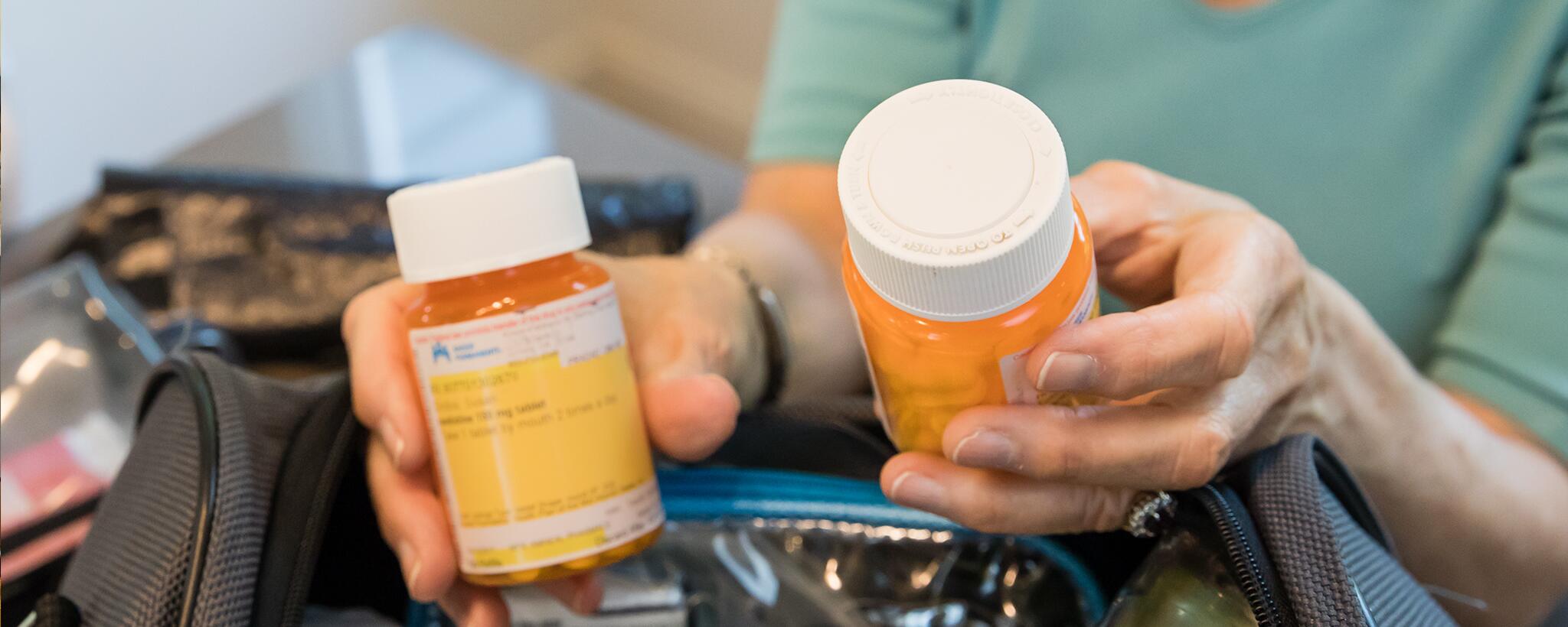 A woman's hands holding two bottles of perscription medications
