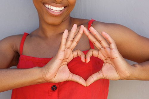 Close up young woman smiling with heart shape hand sign