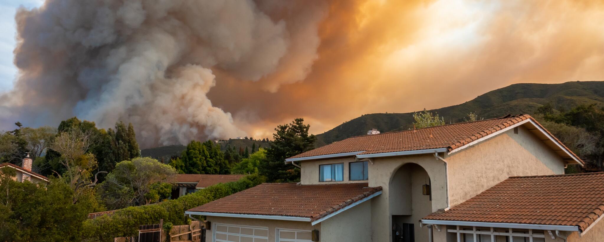 smoke from a wildfire in the background of a house