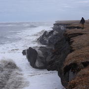 U.S. Geological Survey scientist walks on  a coastal bluff in Alaska.