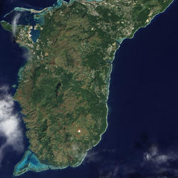 Satellite image of an island showing its terrain, some land features like runways and towns, and the bright shallow waters.