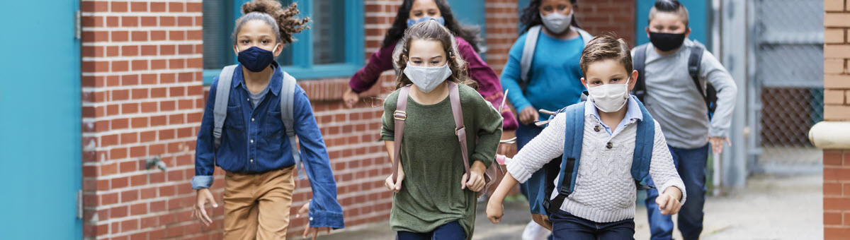 戴着口罩的孩子们在学校教学楼外奔跑