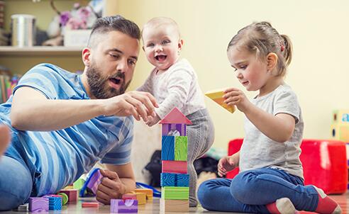 father playing blocks with his two young children