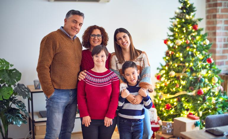 A family standing in front of a Christmas tree at home