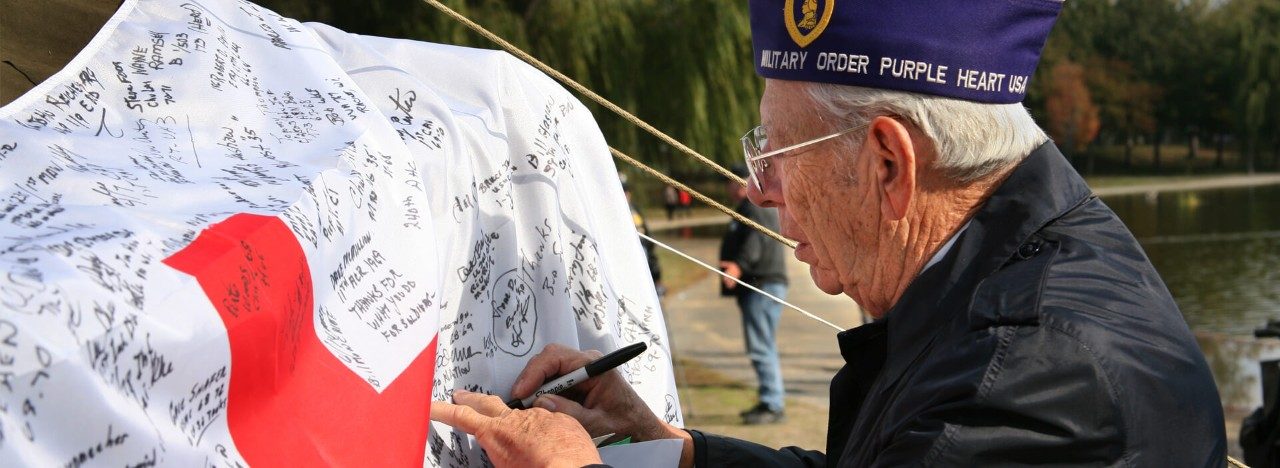 Military veteran signing American Red Cross flag