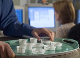 Tray of pills in white paper cups ready for distribution at a facility