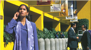 Woman talking on mobile phone in a foreign country. Two officers are conversing in the background.