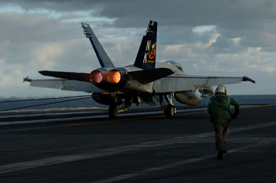 A U.S. Navy aviation boatswain's mate called a tailhook runner rushes toward an F/A-18C Hornet.
