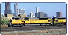 Freight train traveling past city skyline.