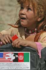An Afghan girl carries school supplies given to her by Marines from Headquarters Company