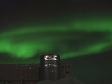 Green lights in night sky above a building.