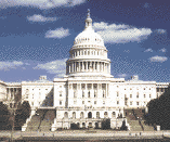 A color photograph of the U.S. Capitol, seen from the West Front.  Two large stairways rise upward on either side, and the Capitol dome rises prominently.