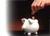 Close-up of a person dropping coins into a piggy bank