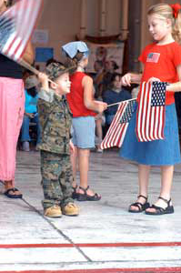 Kendall Carroll watches as her brother, Robert Carroll Jr., excitedly waves the flag as they anticipate the return of their father, Sgt. Robert K. Carroll, from Afghanistan. Photo by: Pfc. James D. Hamel