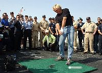 Professional golfer Greg Norman drives a golf ball off the flight deck during his visit to the conventionally powered aircraft carrier USS John F. Kennedy (CV 67).