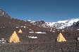 Yellow tents on rocky terrain.