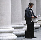 Man reading newspaper in front of columns.