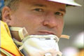 Close-up of an disaster worker's face with a dust mask half way over his mouth.
