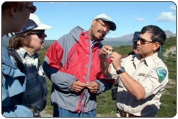 Mientras que Miembros del Consejo Asesor de Alaska escuchan, Arquelogo John Jangala, de la Oficina de Administracin de Tierras en Alaska, explica el significado de un artifacto encontrado en El Distrito Arqueolgico de Tangle Lakes en Julio del 2002.  (Crdito Fotogrfico: Teresa McPherson/BLM-Alaska)