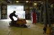 A man driving a snowmobile in a warehouse.