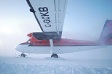 A twin engine airplane, with skis, sits on snow.