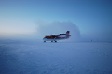 A small airplane with skis sits on the snow.