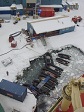 An aerial view of rubber rafts in icy water near a cluster of buildings.