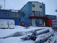 A blue metal building with a snow-covered rubber raft in front of it.