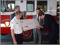 Photo of Regional Director Craig signing a check help by Littlefield, Violette and Allen.