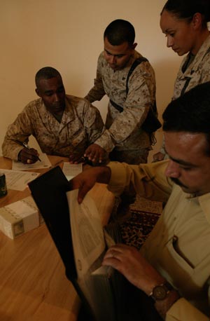 From left to right, Maj. Rollin F. Jackson, project officer, Cpl. Freddy S. Sobalvarro, comptroller chief, Cpl. Maria C. Diaz, payment agent, and Thaer Handala, an Iraqi government representative, complete the signing of a $146,000 contract with the 3rd Battalion, 24th Marine Regiment, at Camp Habbaniyah, Iraq, on June 4, 2004, to install a water purification system in a nearby village. The project will provide safe drinking water for the village of about 1,000 people, who have had to hand-carry and boil lake water or rely on deliveries from the Marines. The work is expected to be completed by the end of June. The project is among many currently being funded by coalition forces to help rebuild Iraq and improve the quality of life for its people. Marines from the reserve infantry battalion provide security for the 1st Force Service Support Group at nearby Camp Taqaddum. Jackson, 37, is a resident of O'Fallon, Mo.; Sobalvarro, 23, is from Miami; and Diaz, 23, is Los Angeles native. Photo by: Sgt. Matt Epright