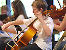 Young cellist rehearsing with other young orchestra musicians