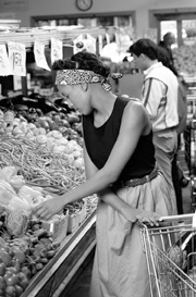 Photo of a woman shopping for vegetables in a grocery store.