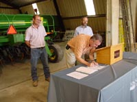 Left to Right: Owner of Borderview Farms (Waldron, MI) Mark Baker with USDA Director of Intergovernmental Affairs James Eichhorst (signing) and acting State Conservationist Barry Kintzer.