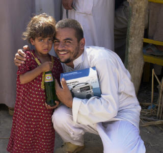 A local man in the village of Al Maejeel poses with his daughter after receiving a radio and a soda from Task Force Danger Soldiers during a recent cordon search in the village south of Samarra. (Photo by Capt. L. Paula Sydenstricker, 196th MPAD)