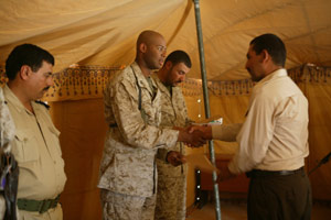 Capt. Carlos T. Jackson, 31, from Detroit and the Commanding officer for Cpmany B, 3rd Assault Amphibian Battalion, gives an Iraqi Border Policeman a graduation certificate during a ceremony held July 19.  Fifteen recruits graduated from the Iraqi Border Police Academy. The academy was the first for western Al Anbar Province. 
(USMC photo by Sgt. Jose L. Garcia) Photo by: Sgt. Jose L. Garcia
