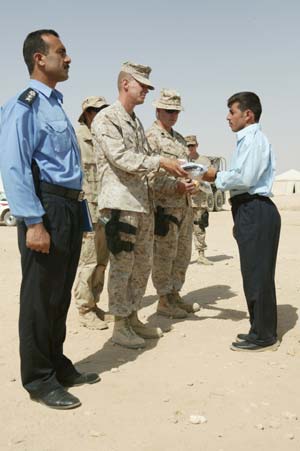 Maj. Quinn D. Auten, a 33-year-old from Columbus, Ohio, hands an Iraqi flag to Dawood Salman, 26, from Baghdaddy, for being the top honor graduate of Camp Al Asad's first Police Academy, July 17. 
(USMC photo by Sgt. Jose L. Garcia) Photo by: Sgt. Jose L. Garcia