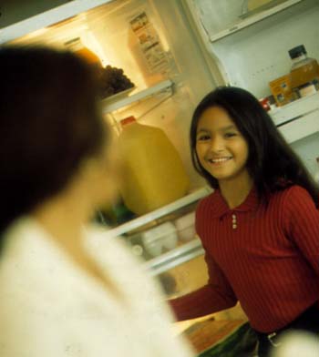 Photo of smiling young teen at open refrigerator.