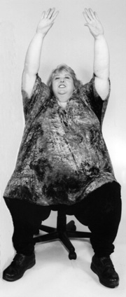 photo of large woman stretching her arms up while seated
