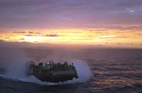 Photo - A Landing Craft Air Cushion (LCAC) returns to USS Oak Hill as the sun sets in the Arabian Gulf.