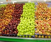Photograph of different kinds of apples on display in the produce department of a grocery store.