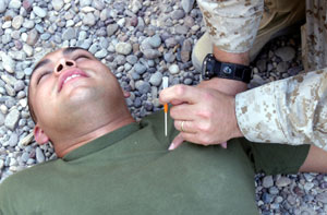 Cpl. Jorge A. Medina, 21, a native of National City, Calif., and a warehouse clerk with supply, Headquarters Company, Regimental Combat Team 1, acts as a casualty at a Marine combat aidsman course as the instructor shows the students how and when to apply a needle thoracentesis on Oct. 14 in Camp Fallujah, this procedure would be attempted if the victim was suffering from a traumatic chest wound. Photo by:Lance Cpl. Miguel A. Carrasco Jr.