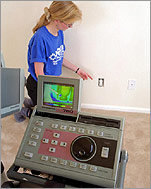 Photo of researcher testing energy efficiency of an electric outlet in a home.
