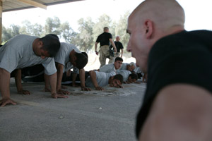 1st Lt. Sean M. Gavigan, officer-in-charge of the Al Qaim Police Academy and from New City, N.Y., yells to his 40 students to properly do their push-ups April 13th.  The academy, which is the first of its' kind, will graduate a class Aprl 17th.  The 21-day course will train approximately 500 students throughout the year by Marine instructors.  
(USMC Photo by Lance Cpl. Macario P. Mora Jr.) Photo by: Lance Cpl. Macario P. Mora Jr.