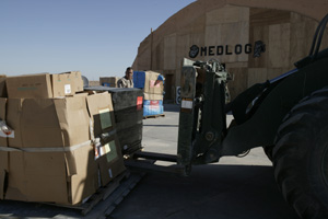 Cpl. Angelbert Munoz, with 1st Force Service Support Group's medical logistics section, directs a heavy forklift in unloading part of an $810,000 shipment of medical supplies in front of their compound April 1, 2004, at Camp Taqaddum, Iraq. The supplies, which are being delivered to the local Iraqi population, were purchased by the Freedom and Peace Trust using funds donated by U.S. corporations. The 1st FSSG's medical logistics section helped coordinate the transportation of the supplies from the United States, through Kuwait, to the camp. The supplies will eventually be distributed by the 1st Marine Division to the Iraqi people. Medical logistics oversees the ordering and delivery of medical supplies for I Marine Expeditionary Force, currently in Iraq to conduct security and stability operations. Munoz is a 24-year-old native of Apple Valley, Calif., and Welch, 21, is a San Diego native. Photo by: Sgt. Matt Epright