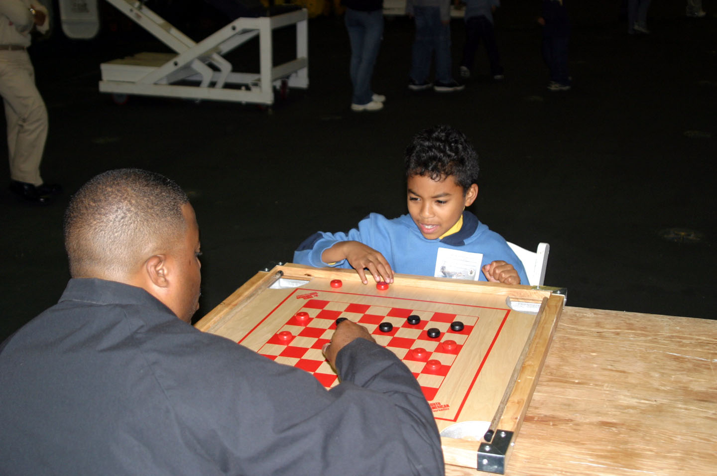ABOARD USS CARL VINSON, At Sea in the Puget Sound -- A USS Carl Vinson (CVN 70) crew member and his son play checkers in the Hangar Bay Saturday during the "Gold Eagle" Friends and Family Day Cruise. More than 2,000 guests of the ship got a taste of underway life, complete with an air show, games and static displays of common evolutions aboard the Nimitz-class aircraft carrier. Photo by JOC(SW/AW) Eric Harrison.