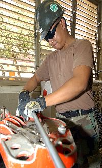 Engineering Aide 2nd Class Richard Vilar, assigned to Naval Construction Battalion Unit Four One Three (CBU-413), cuts electrical piping for a new wall.