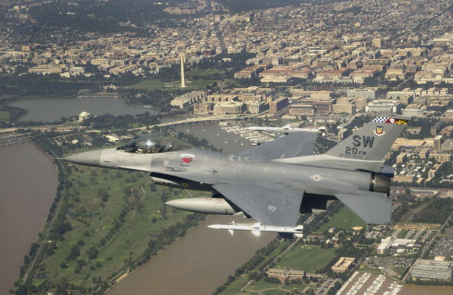 An F–16 flies over Washington, D.C. with the Washington Monument in the background.